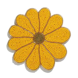 Detalle de posavasos de girasol con cuentas hechas a mano, mantel de flores amarillas.
