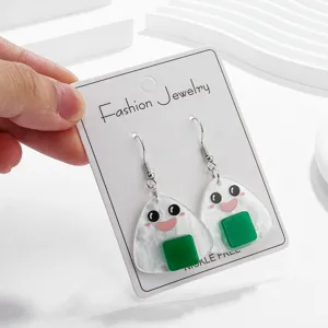 Vue détaillée de charmantes boucles d'oreilles pendantes en acrylique onigiri avec sourires.