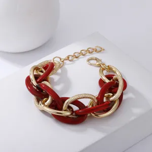 Detailansicht des klobigen Statement-Armbands mit roten Acryl- und goldenen Metallringen.