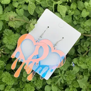 Detailansicht bunter, verlaeuferischer Acryl-Herz-Ohrringe mit Metallhaken auf Rasen.