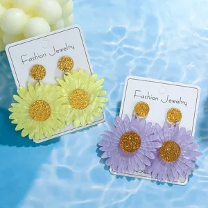 Detailansicht glänzender Acryl Blumenohrringe mit glitzerndem Kern in Gelb und Lila.