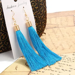 Detailaufnahme lange blaue Quasten Ohrringe mit goldenem Haken, eleganter Boho Schmuck.