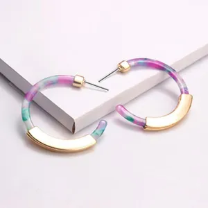 Nahaufnahme der bunten Acetat-Acryl-Creolen mit eleganten goldenen Metallakzenten auf weißer Box.
