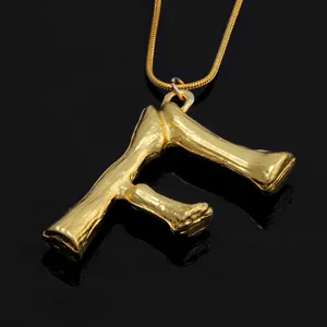 Goldene Knochen-Textur Buchstabe F Anhänger Halskette, Detail-Nahaufnahme der trendigen Punk-Kette.