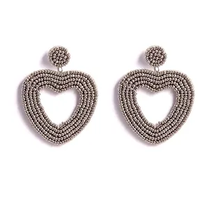 Detaillierte Nahaufnahme von handgemachten Perlen-Herz-Ohrringen in Silber, Boheme-Schmuck.