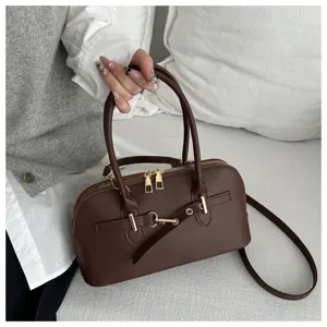 Detailed view of the dark brown leather handbag with metal buckle and dual handles.