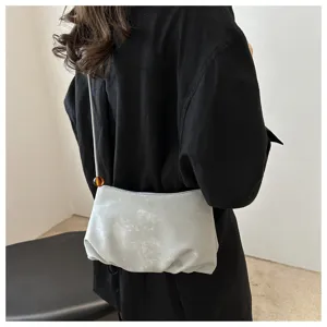 Vista detallada de un elegante bolso cruzado fruncido con correa fina y cuenta.