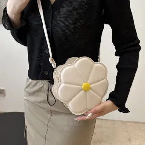 Detail van de hippe witte bloemvormige schoudertas met een schattige gele knop.