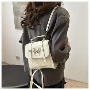 Small women backpack in beige with metal butterfly detail, stylish lightweight mini travel bag.