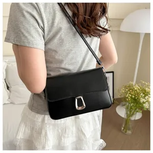 Close-up detail of the elegant black shoulder bag showing texture, metal clasp and strap.
