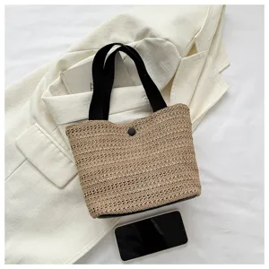 Straw woven bucket tote bag with black handles and snap closure for women daily use.