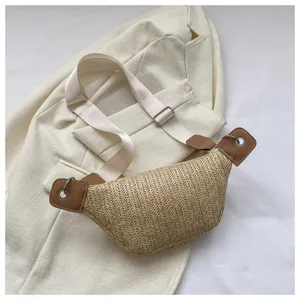 Borsa da petto in paglia intrecciata alla moda con tracolla larga e dettagli in pelle.