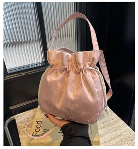 Primo piano dettagliato della borsa a secchiello in satin rosa con delicati motivi e strass.