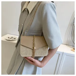 Woven straw crossbody bag detail, chic tan leather flap, elegant metal chain and tassel.