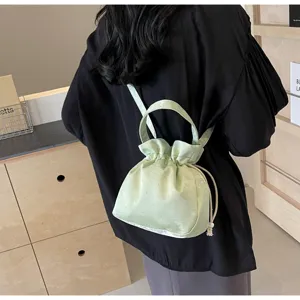 Borsa a secchiello in raso verde chiaro con coulisse, elegante stile a spalla e a mano.