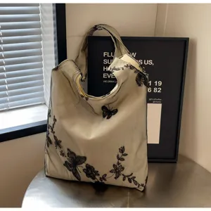 Elegante beige Canvas Schultertasche mit zarter schwarzer Schmetterling Stickerei für Damen.