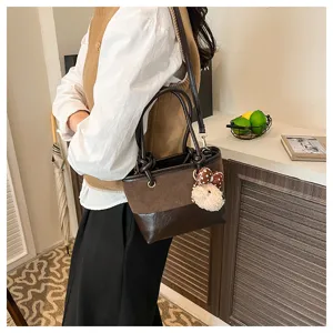 Retro braune Leder Eimer Tasche Detail mit süßem Plüsch Bär Anhänger und Schultergurt.