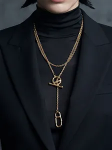 Close-up of vintage gold layered T-bar necklace worn with black blazer for elegant style.