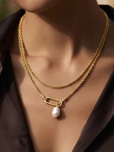 Close-up of layered gold chain necklace featuring a unique baroque pearl pendant.