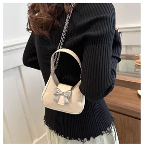 Dettaglio borsa a mano bianca con fiocco chic, catena elegante e raffinato accessorio.