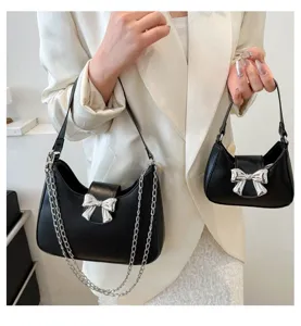 Borsa a tracolla nera chic con fiocco argento e catena, accessorio di dettaglio elegante.