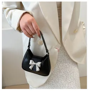 Primo piano di una chic borsa a mano nera con un dettaglio di fiocco metallico argentato.