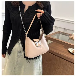 Vista dettagliata della borsa a spalla rosa con grazioso fiocco e tracolla a catena chic.