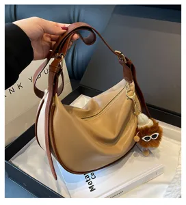 Details der braun-beigen farbblockierenden Hobo-Umhängetasche mit süßem Plüschanhänger.