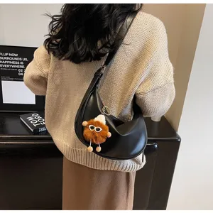 Detailansicht einer stilvollen schwarzen Kunstleder Hobo Schultertasche mit Plüschanhänger.