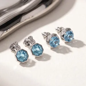 Detailed close-up of sparkling blue zircon and diamond stud earrings with elegant silver setting.