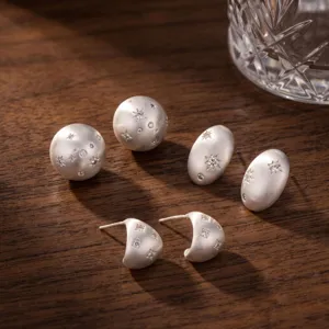 Primo piano di orecchini argentati opachi con zirconi cubici scintillanti a stella.