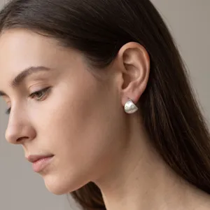 Primo piano di orecchini a lobo rotondi in argento opaco con delicati zirconi scintillanti.