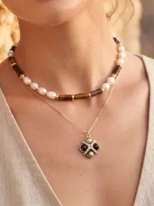 Close-up detail of layered pearl and stone necklace with elegant pendant, fashion jewelry shot.