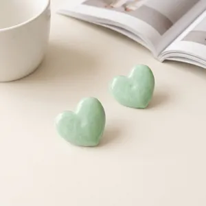 Mint green heart stud earrings close-up detail, elegant minimalist resin daily jewelry accessory.