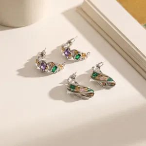 Primo piano dettagliato degli orecchini strutturati irregolari con zirconi colorati e foglia oro.