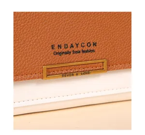 Gros plan détail du sac portefeuille bicolore marron et blanc ENDAYCON avec boucle élégante.