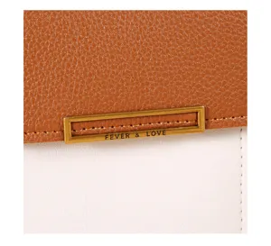 Detalle de primer plano de bolso para móvil de cuero bicolor con placa metálica.