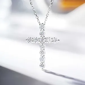 Detailed shot of a sterling silver cross pendant necklace sparkling with fine moissanite stones.