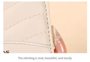 Detailopname van beige gewatteerde portemonnaie met net stiksel en fijne textuur.