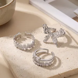 Primo piano dettagliato di tre anelli regolabili in argento con zirconi cubici e design a farfalla.