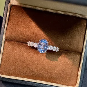 Primo piano di uno splendido anello con gemma blu ovale che brilla elegantemente in un astuccio.