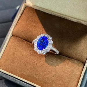 Detailaufnahme eines königsblauen Saphirrings mit Diamantkranz in einer braunen Schachtel.