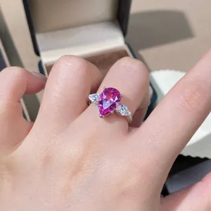 Detailopname van een roze saffier driesteen zilveren ring om de vinger gepresenteerd.