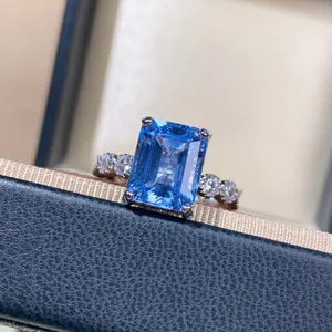 Stunning emerald-cut blue aquamarine gemstone ring detail, sparkling silver side stone setting.