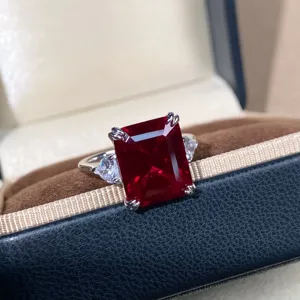Emerald cut lab created ruby ring detail, sparkling red gemstone with side stones in silver setting.
