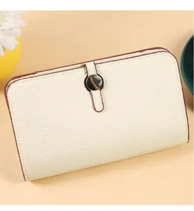 Detalle del elegante bolso cartera de cuero beige con cierre de botón metálico para teléfono.