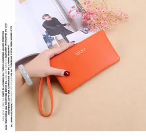 Primer plano de elegante cartera larga de piel PU naranja con correa de muñeca y texto.