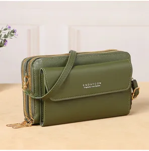 Green multi-layer crossbody phone bag detail, showing dual zippers and front flap pocket.