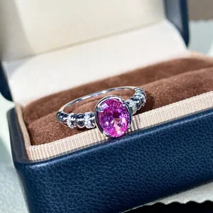 Primo piano dettagliato dell'elegante anello in zaffiro rosa con fascia in argento perlato.