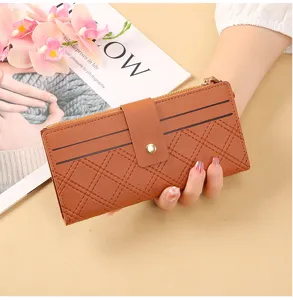 Detailed view of women's brown long wallet with quilted pattern, snap button and zipper closure.